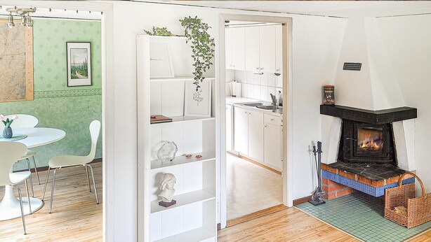 A modern kitchen with a built-in fireplace, white cabinetry, and a dining area with a round table and chairs. - Stunning home in Annerstad with WiFi (Annerstad)