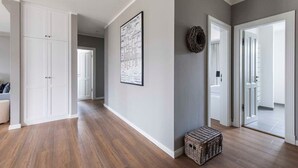 Ein Korridor mit Holzdielen, weißen Türen und einem gerahmten Bild an der Wand.