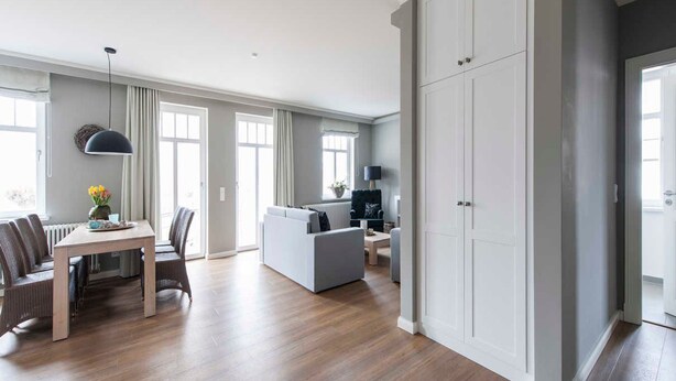 Ein großzügiger Wohnbereich mit Esstisch, Sofa und großem Kleiderschrank.