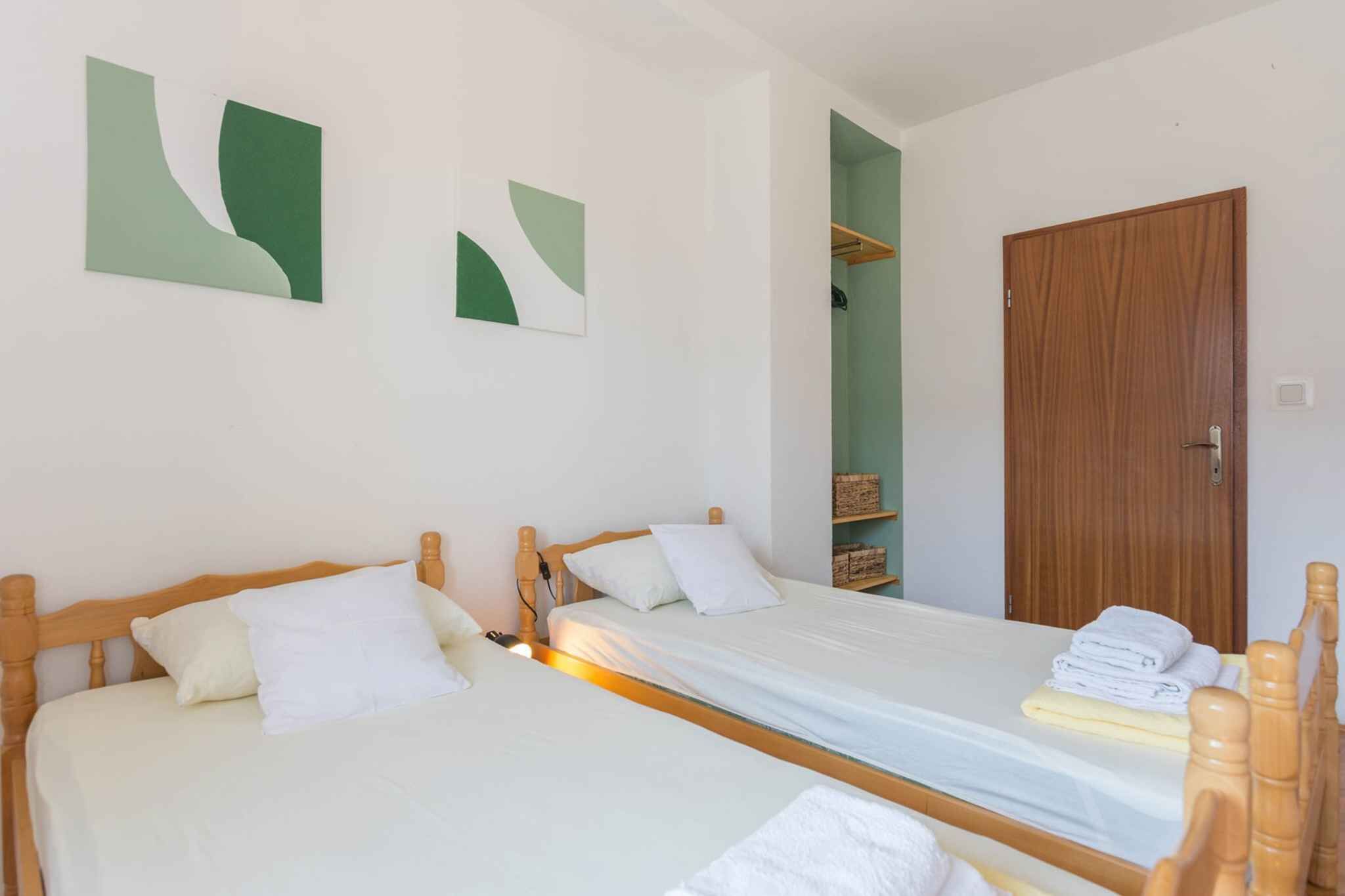 Ein Zimmer mit zwei Einzelbetten, einem Holzschrank und abstrakter Wandkunst.