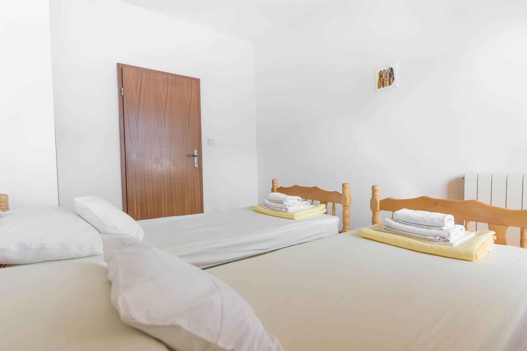 Une chambre d’hôtel avec deux lits, des têtes de lit en bois, du linge de lit blanc et une porte en bois.