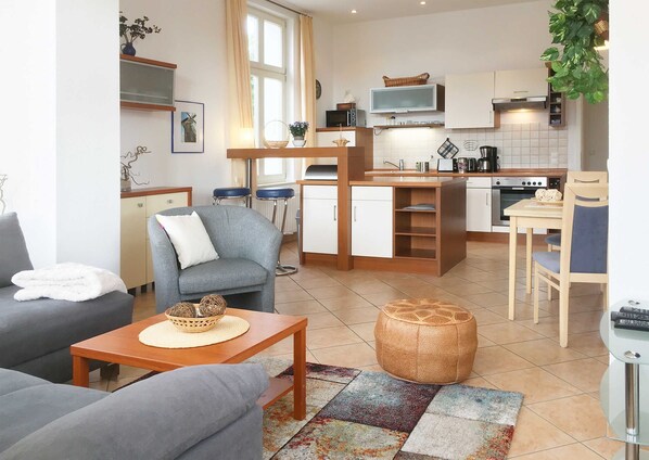 Un salon moderne avec un canapé gris, une table basse en bois et un tapis coloré.