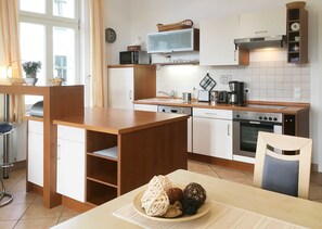 A compact kitchen with a wooden island, white cabinets, a built-in microwave, and a stove.