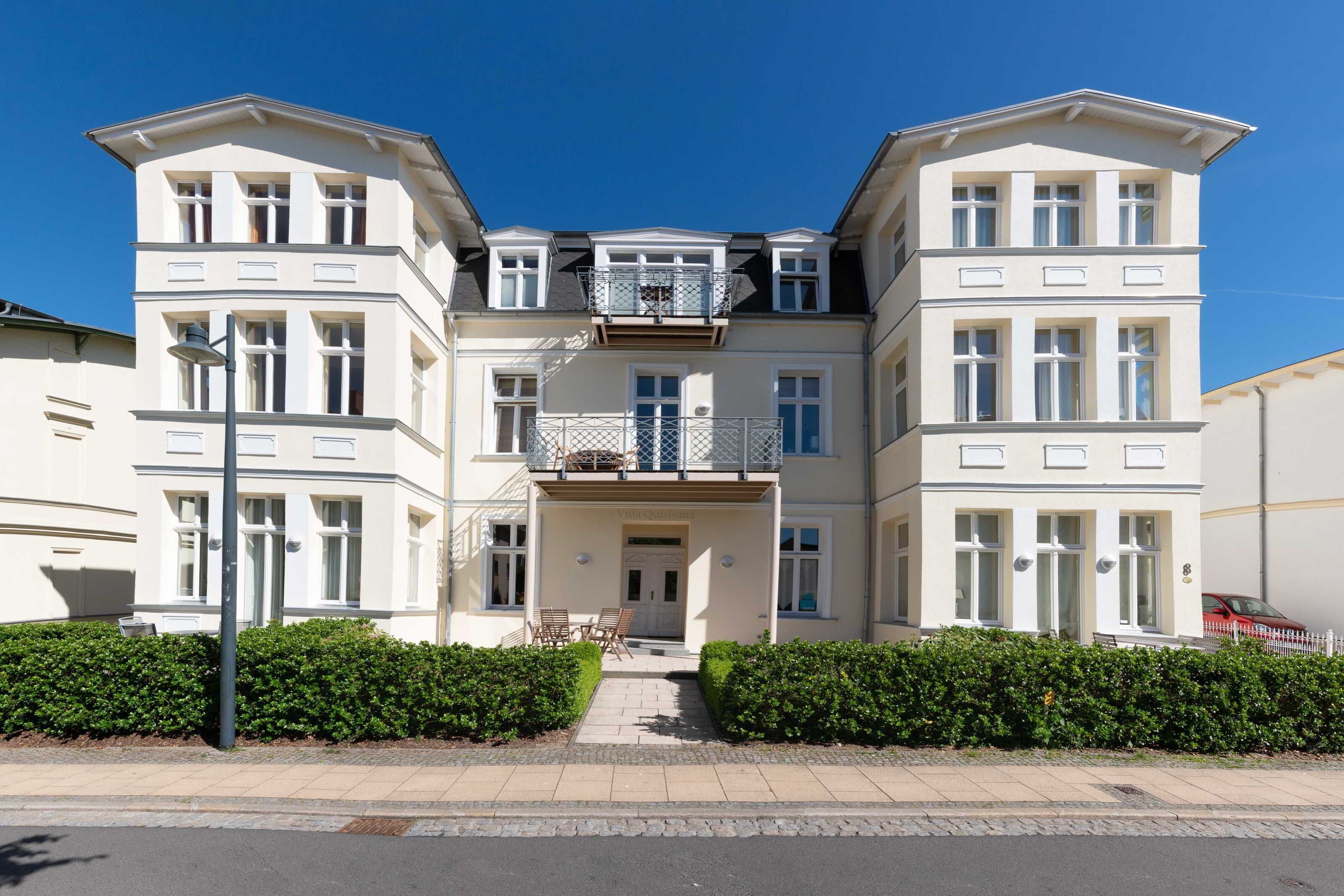 A multi-story residential building with a symmetrical facade, large windows, and a central entrance with a door and steps.