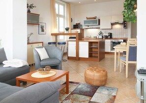 A modern living room with a grey sofa, a wooden coffee table, and a colorful rug. - Apartment 4 - Villa Quisisana (Heringsdorf)