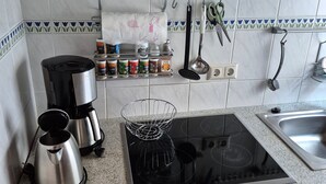 A kitchen with a stove, coffee maker, and various kitchen utensils. - Vacation home Boddenblick (Barth)