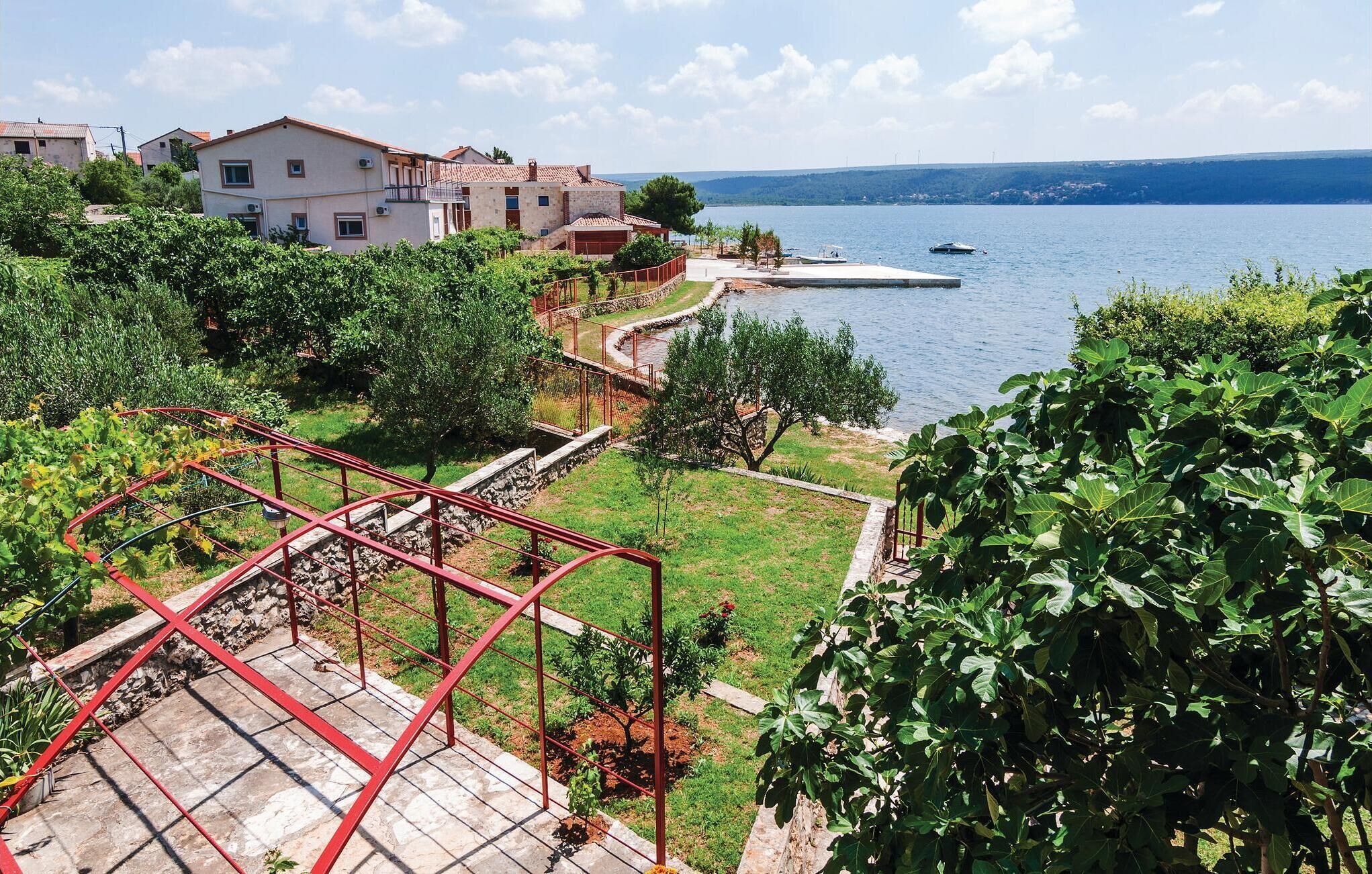 Ein Küstenanwesen mit Garten, einer roten Metalltreppe und Meerblick.