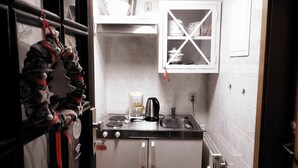 Una cocina compacta con estufa integrada, cafetera y un mueble pequeño.