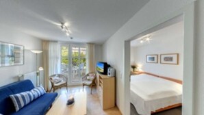 Une chambre d’hôtel comprenant un lit, un bureau avec un ordinateur, une chaise, un canapé et un téléviseur.