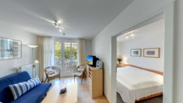 Une chambre d’hôtel comprenant un lit, un bureau avec un ordinateur, une chaise, un canapé et un téléviseur.