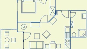 Un plan d’étage comprenant une cuisine, un coin repas et un salon avec un canapé et un téléviseur.