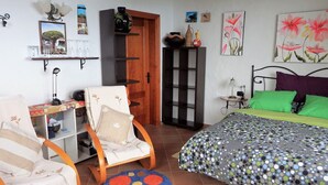 Een slaapkamer met een bed, een stoel, een bureau en een kledingkast.