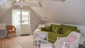 A cozy attic bedroom with a green sofa, a wicker chair, and a small white table. - Nice home in Löttorp with WiFi (Löttorp)