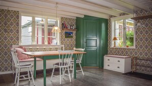 A cozy kitchen with a wooden table, white chairs, a green door, and patterned wallpaper. - Nice home in Löttorp with WiFi (Löttorp)