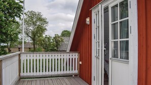 A wooden deck with a white picket fence, a red building with a white door, and a clear sky. - Nice home in Löttorp with WiFi (Löttorp)