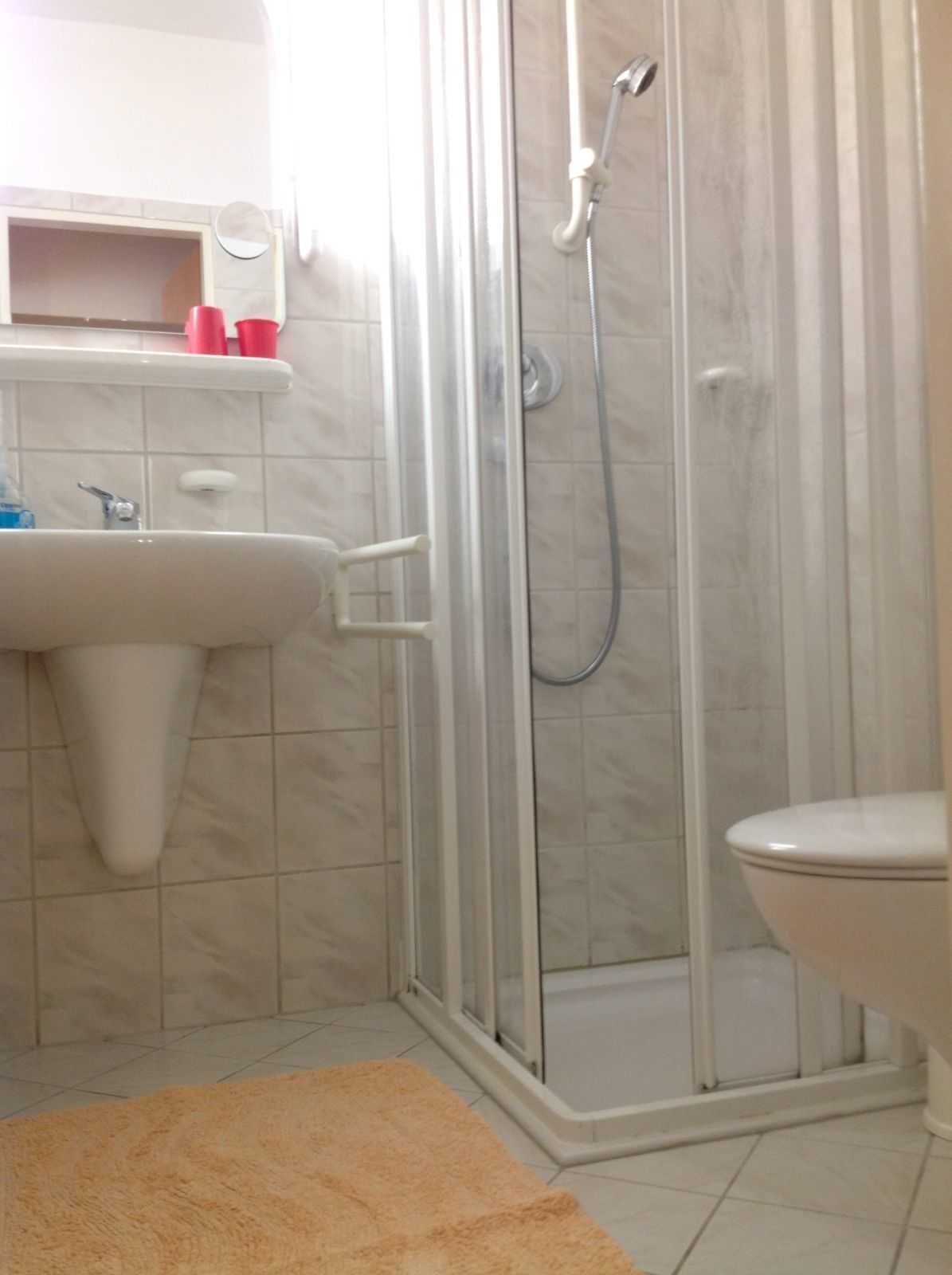 Une salle de bain avec une douche à parois de verre, un lavabo et des toilettes.