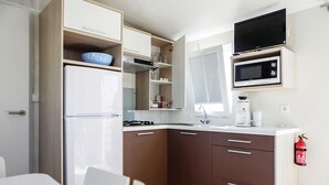 A compact kitchen with a refrigerator, microwave, stove, and a coffee maker.