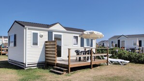 A mobile home with a deck, outdoor furniture, and a patio umbrella.