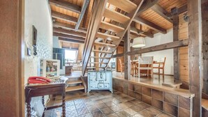 A rustic wooden interior with exposed beams, a dining area with wooden chairs, and a kitchen with a vintage stove.