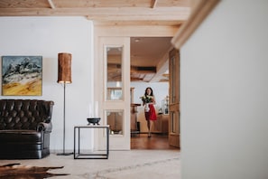 A living room with a leather sofa, a painting, a floor lamp, and a small table.