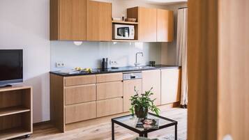 A modern kitchen with wooden cabinets, a microwave, and a sink.