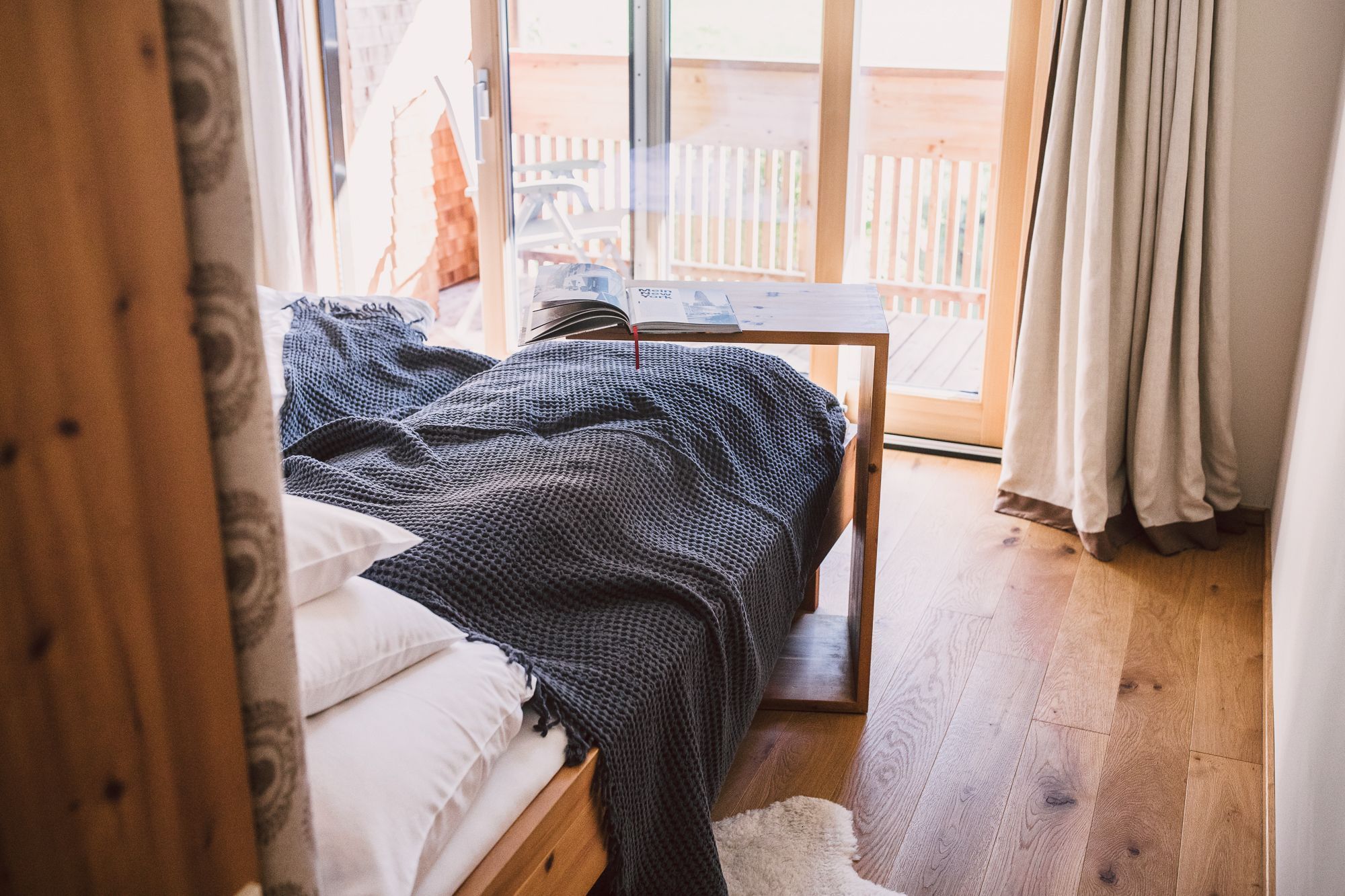 Un dormitorio con cama, una mesita y vistas al exterior.