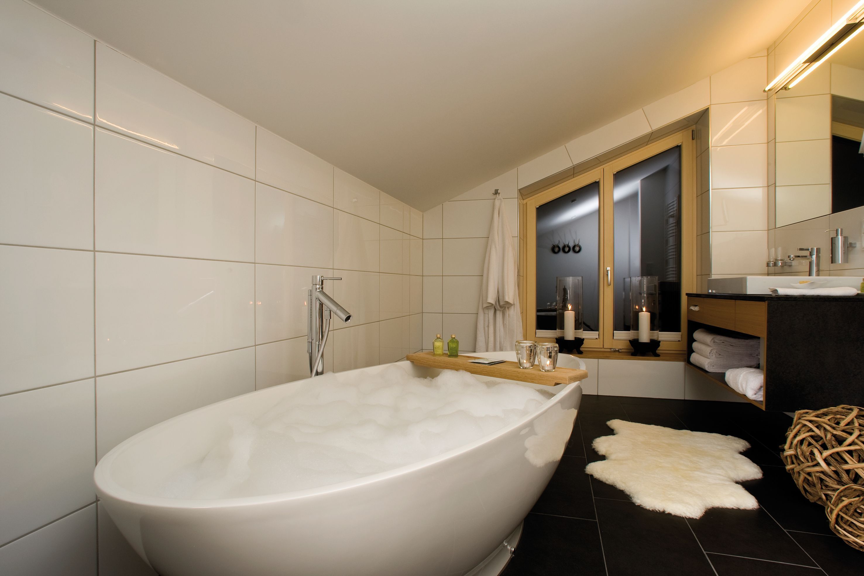 Ein modernes Badezimmer mit einer freistehenden Badewanne, einem Holzbadezimmermöbel, einem Spiegel und einem Handtuchhalter.