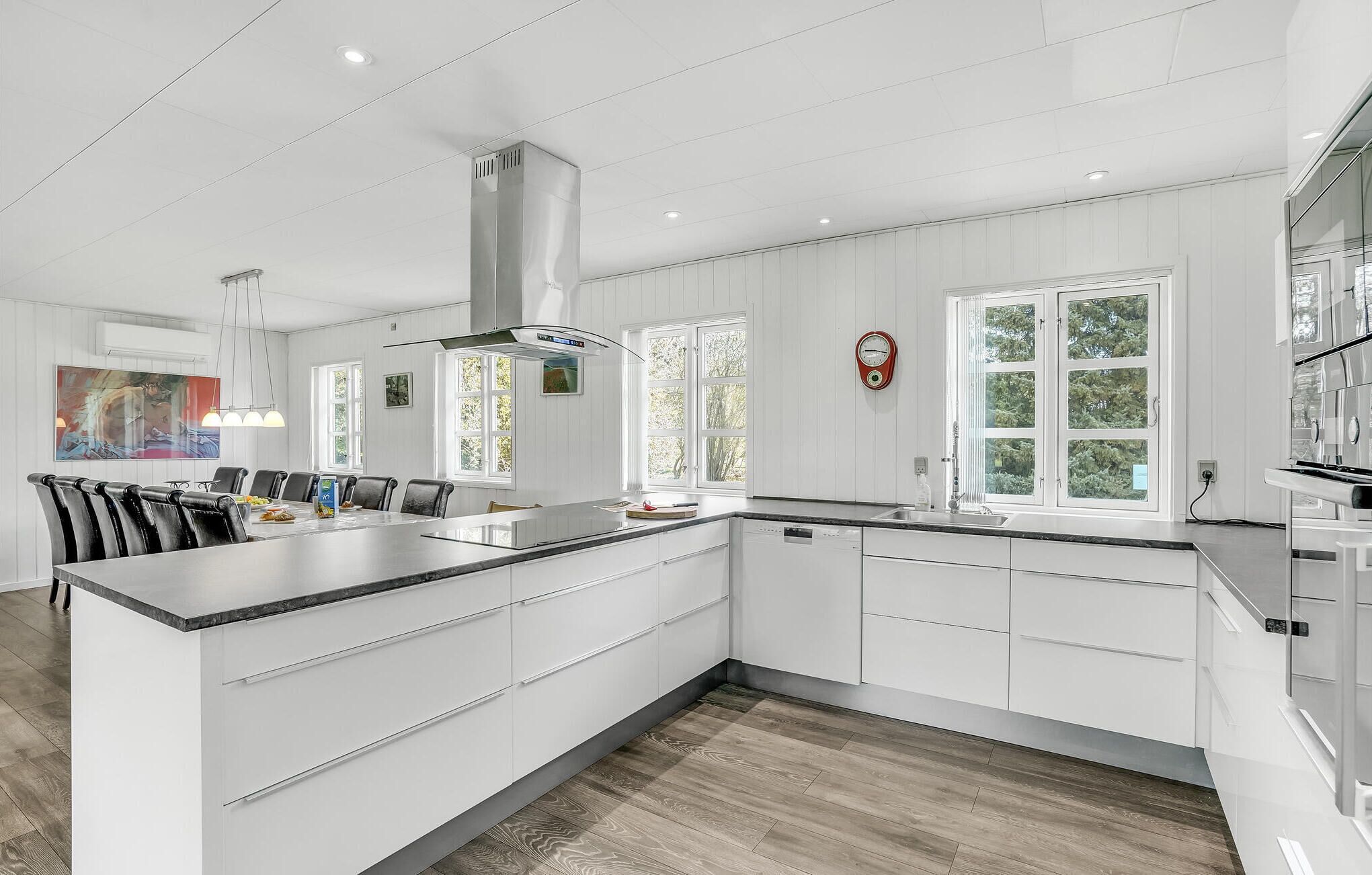 Una cocina moderna con armarios blancos, una isla grande y un comedor con mesa y sillas.