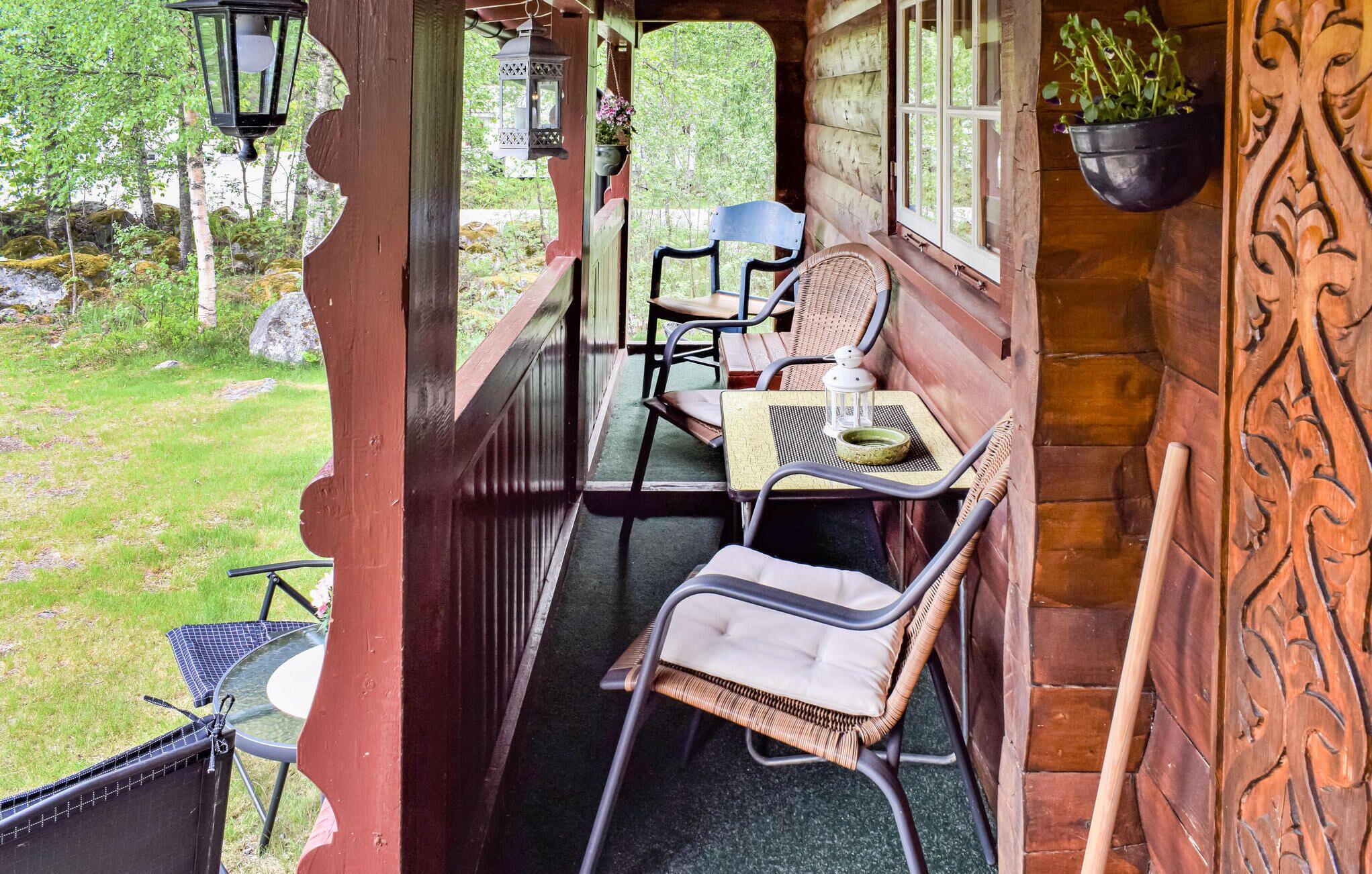 Un portico in legno con due poltrone in vimini, un tavolino e fioriere appese.