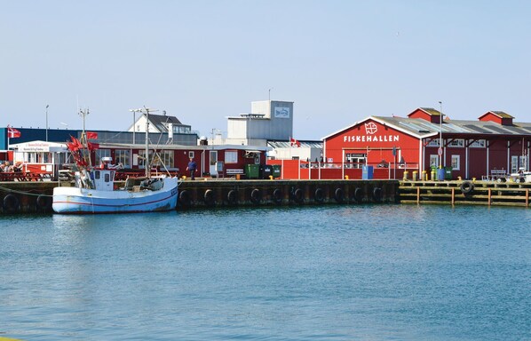 Ein Hafen mit einem roten Gebäude, auf dem 'FISKEHALLEN' steht, und einem dort liegenden Boot.