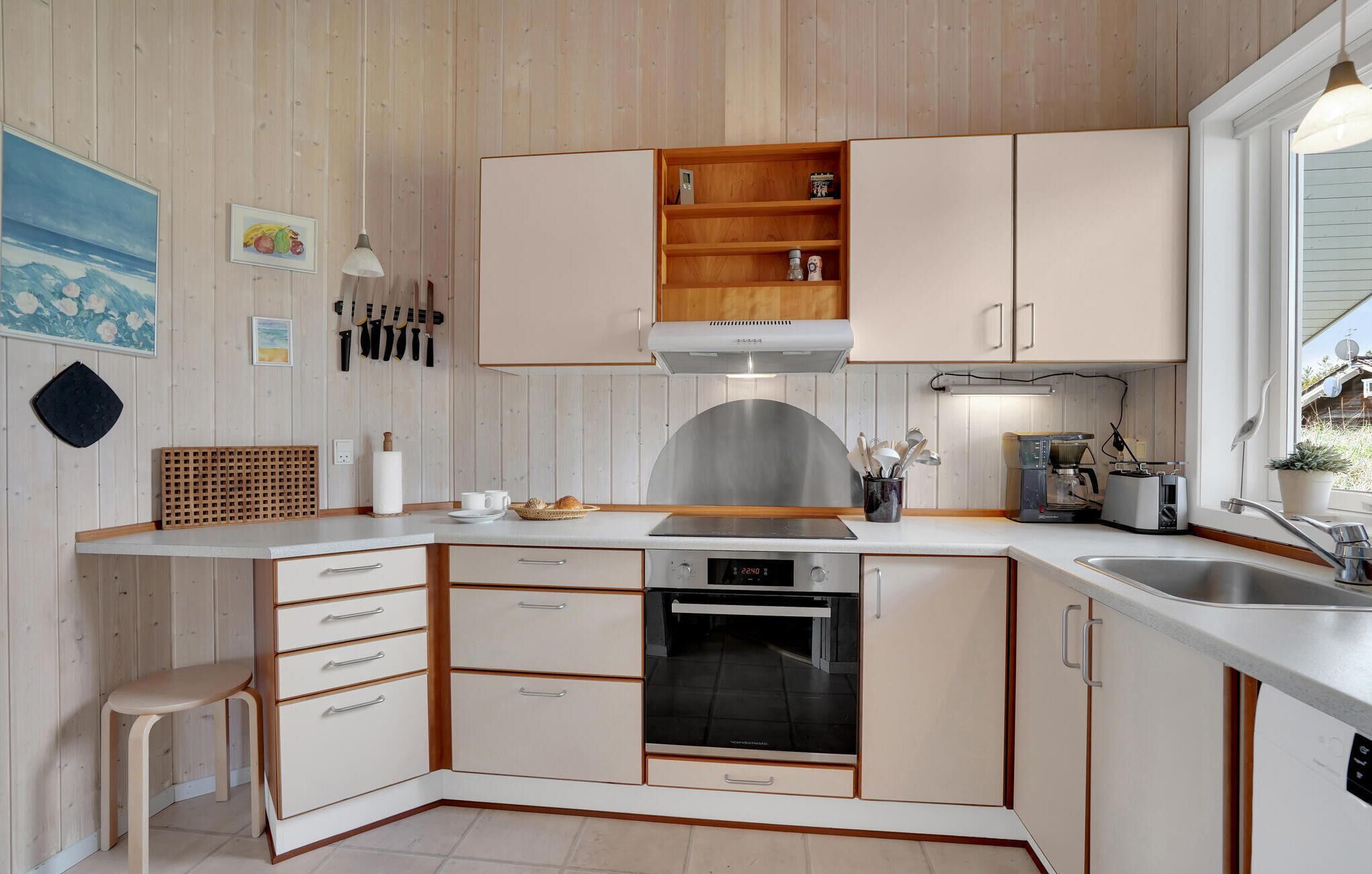 A modern kitchen with white cabinetry, a built-in oven, and a countertop with a coffee maker and toaster.