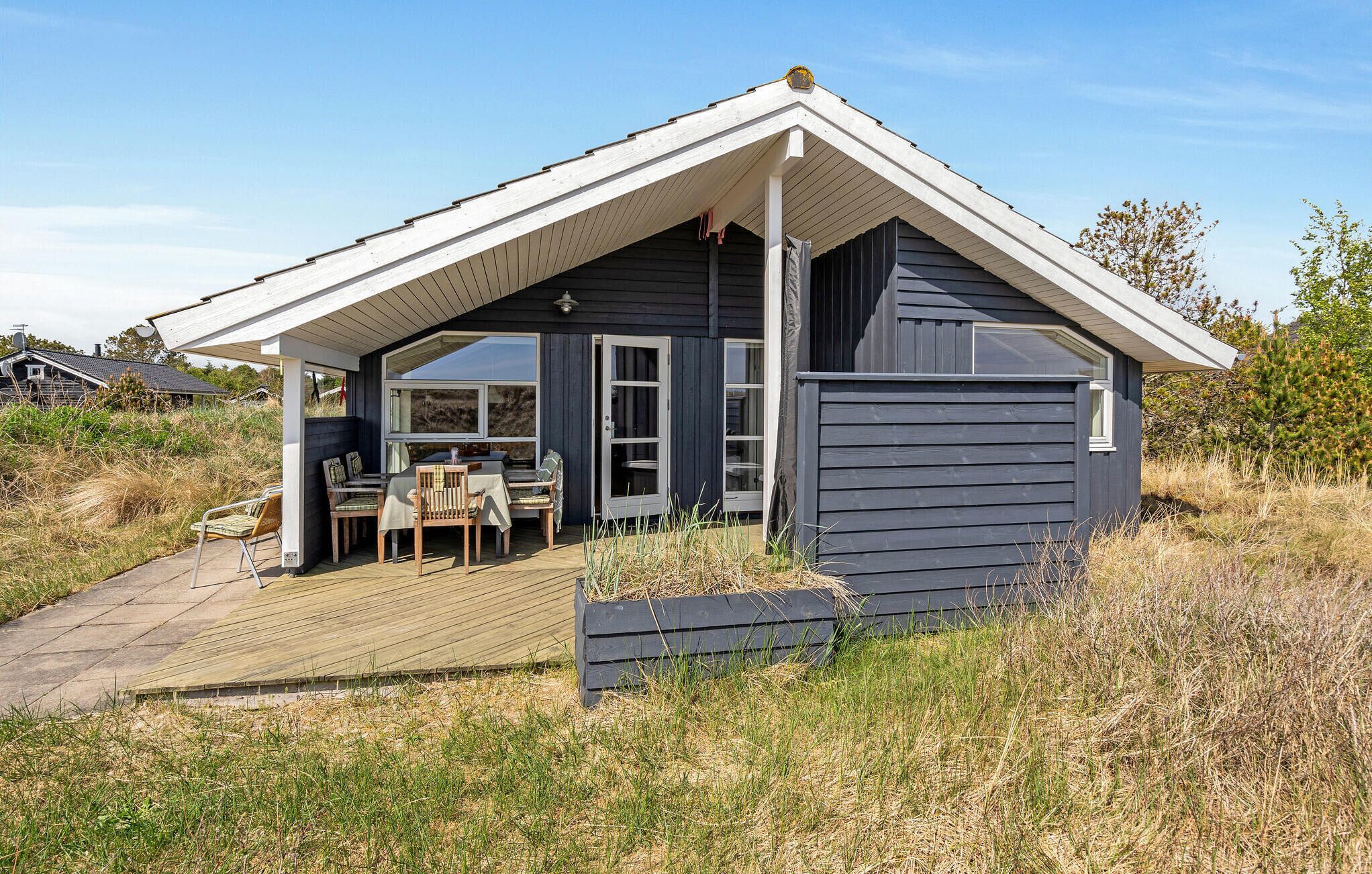 A small, dark-colored cabin with a sloped roof and a covered porch.