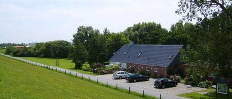 A rural property with a large house, a fenced driveway, and several parked cars.