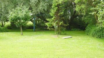 A grassy outdoor area with trees and a swing set.