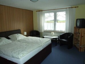 Une chambre d’hôtel équipée d’un lit, d’un bureau, d’une chaise, d’une télévision et d’une fenêtre avec des rideaux.