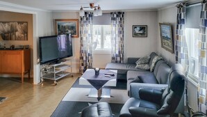 A modern living room with a flat-screen TV, a sofa, a coffee table, and a dining area with a wooden table and chairs. - 3 bedroom lovely home in Vetlanda (Vetlanda)