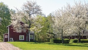 A red building with a white porch, surrounded by blooming trees and a well-maintained lawn. - 3 bedroom lovely home in Vetlanda (Vetlanda)
