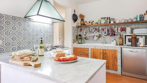 Una cocina con salpicadero decorado, armarios de madera, un refrigerador de acero inoxidable y una variedad de utensilios de cocina colgados en la pared.