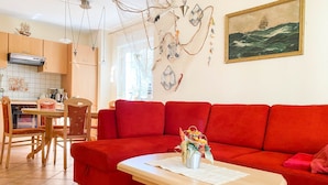 A living room with a red sofa, a wooden coffee table, and a painting of a ship on the wall. - *Forest 10 measure GM 69552 - Forest 10 - SNR: 1 (Graal-Müritz)