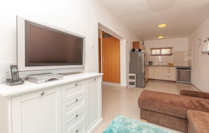 A modern living room with a flat-screen TV, a remote control, and a small console. There is a brown sofa and a blue rug. - 2 bedroom beach front apartment in Pirovac (Pirovac)