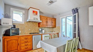 Une cuisine compacte avec des meubles en bois, un four encastré, un évier et un coin repas comprenant une table et des chaises.
