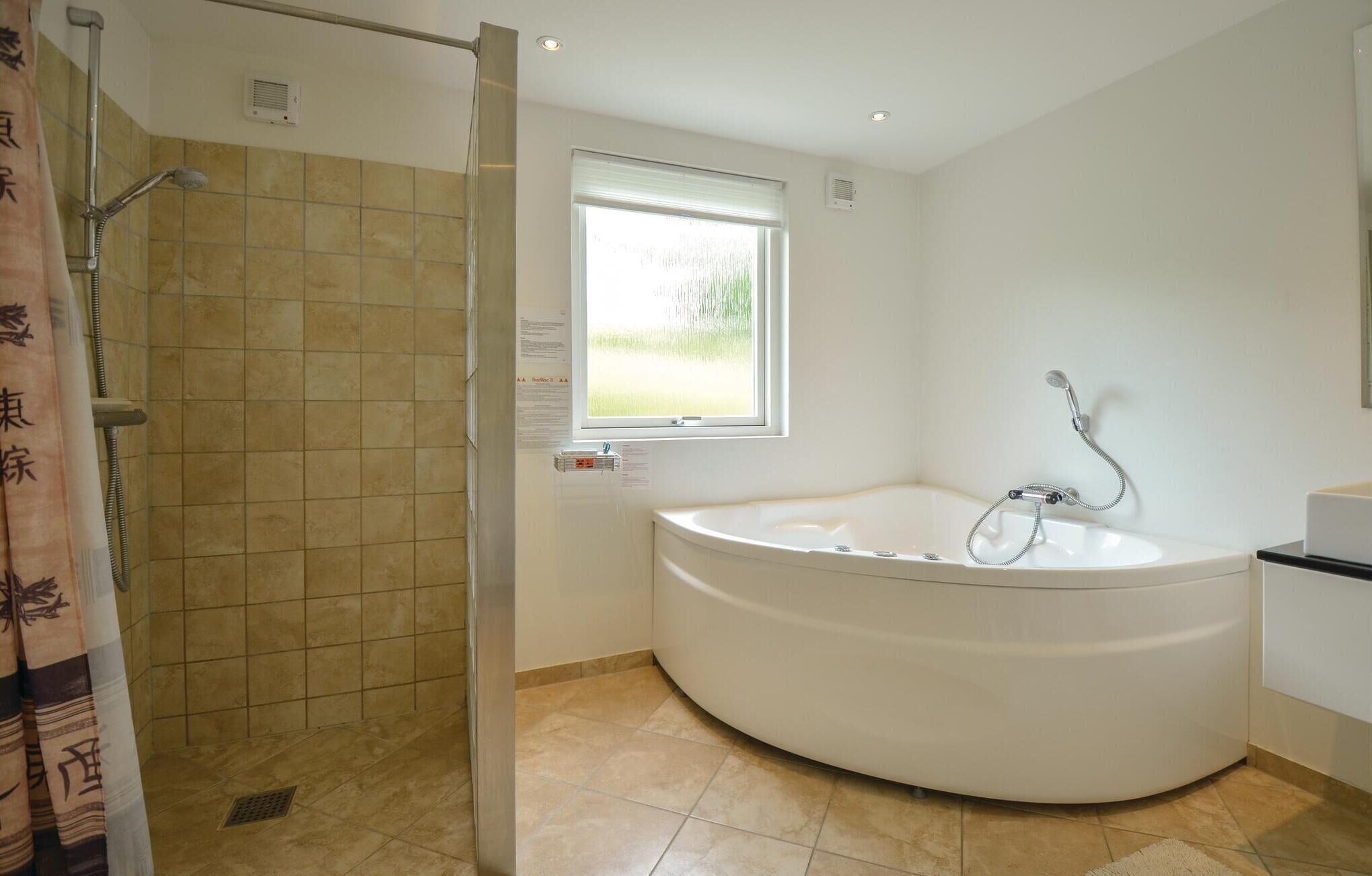 Une salle de bain moderne dotée d’une douche à l’italienne, d’une baignoire sur pieds et d’une fenêtre laissant entrer la lumière naturelle.
