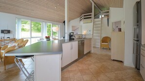 Una cocina moderna con una isla grande, armarios blancos y vistas al exterior.