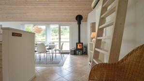 Una sala de estar acogedora con chimenea, un comedor con sillas y una butaca de mimbre.
