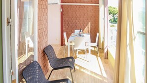An open patio with a brick wall, a table with chairs, and a bottle of wine. - Cozy apartment in Alicante with WiFi (Alicante)