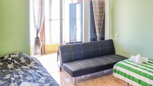 A room with a sofa, a bed with a striped bedspread, and curtains on the windows. - Cozy apartment in Alicante with WiFi (Alicante)
