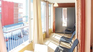 A balcony with a table and chairs, a sliding door, and a view of the street. - Cozy apartment in Alicante with WiFi (Alicante)
