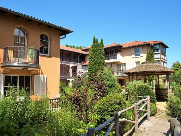 Un hotel con varios balcones, una terraza de madera y abundante vegetación.
