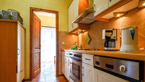 Cocina compacta con estufa, horno y cafetera.