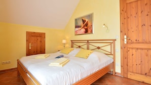Un dormitorio con una cama de madera, un cuadro en la pared y una puerta grande de madera.